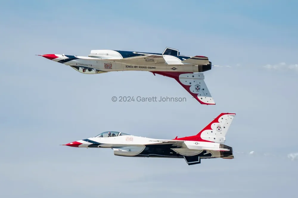 Two Thunderbirds F-16s fly canopy to canopy, one inverted above the other, against a pale blue sky at the Duluth airshow.